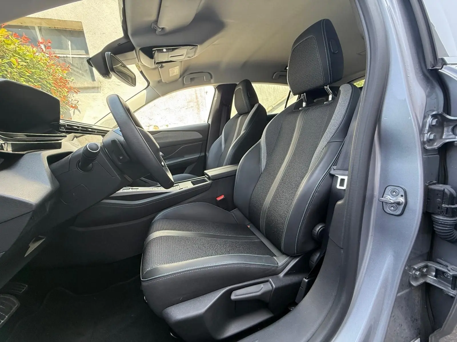 Intérieur avant droit de la Peugeot 308 2024 gris Artense, sièges tissu et cuir avec surpiqûres contrastées.
