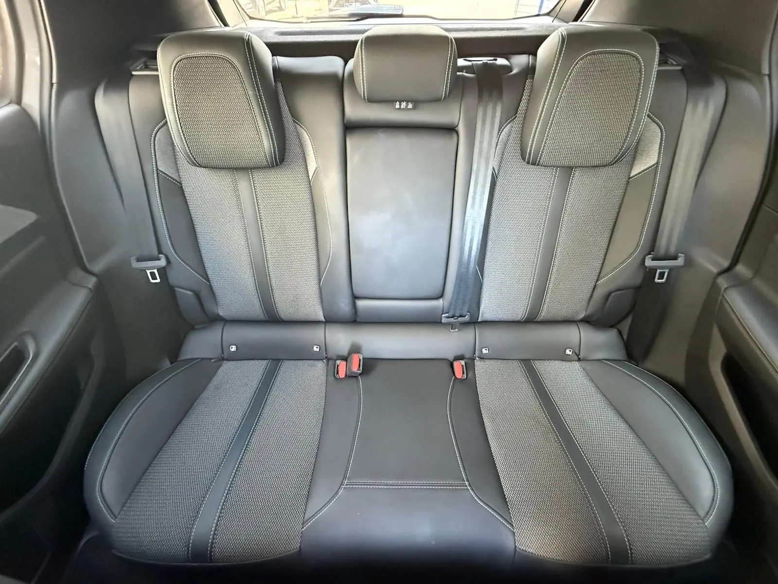 Vue intérieure arrière des sièges en cuir noir et tissu gris de la Peugeot 308 2024 finition Allure.