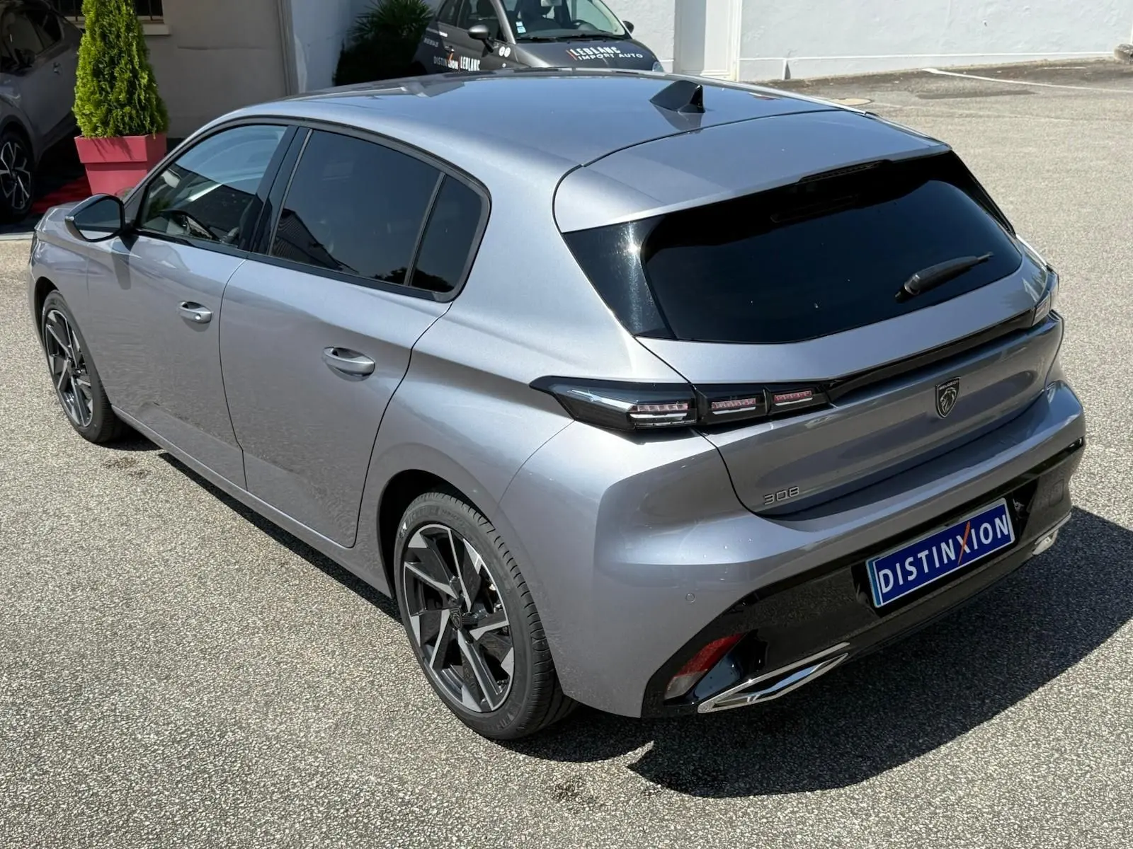 Vue 3/4 arrière droite d'une Peugeot 308 gris Artense 2024 avec feux LED et jantes alliage distinctives.
