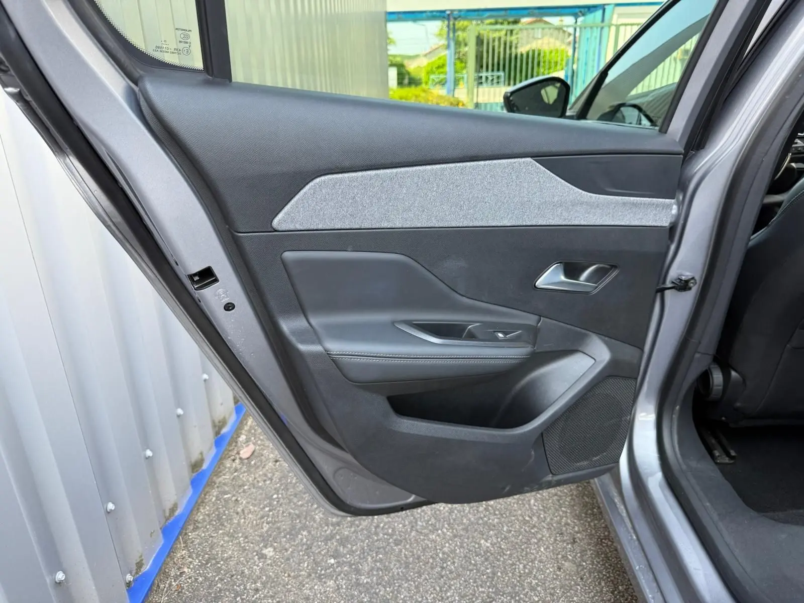 Vue intérieure de la porte arrière gauche d'une Peugeot 308 gris Artense avec garniture noire et tissu gris clair.