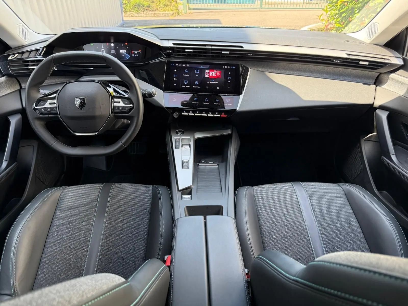 Intérieur de la Peugeot 308 2024 en gris, vue frontale du tableau de bord avec écran tactile et volant multifonction.