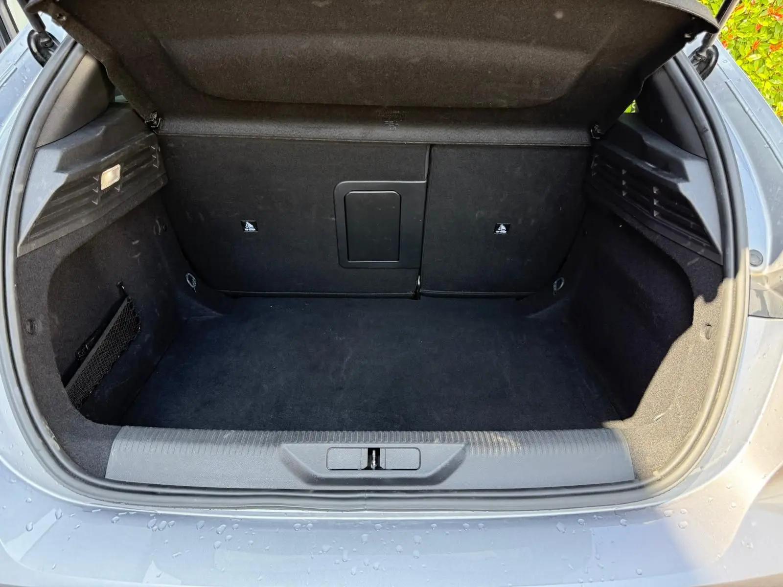 Coffre ouvert d'une Peugeot 308 gris Artense, vue arrière montrant un espace de chargement propre et spacieux.
