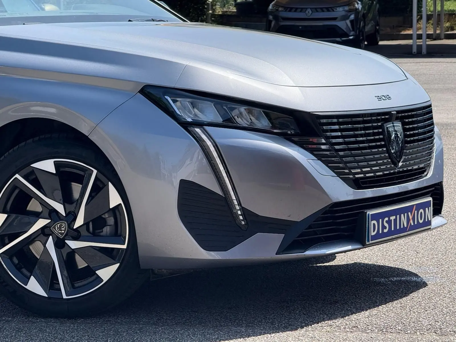 Vue 3/4 avant droit de la Peugeot 308 gris Artense avec calandre noire et jantes alliage distinctives.