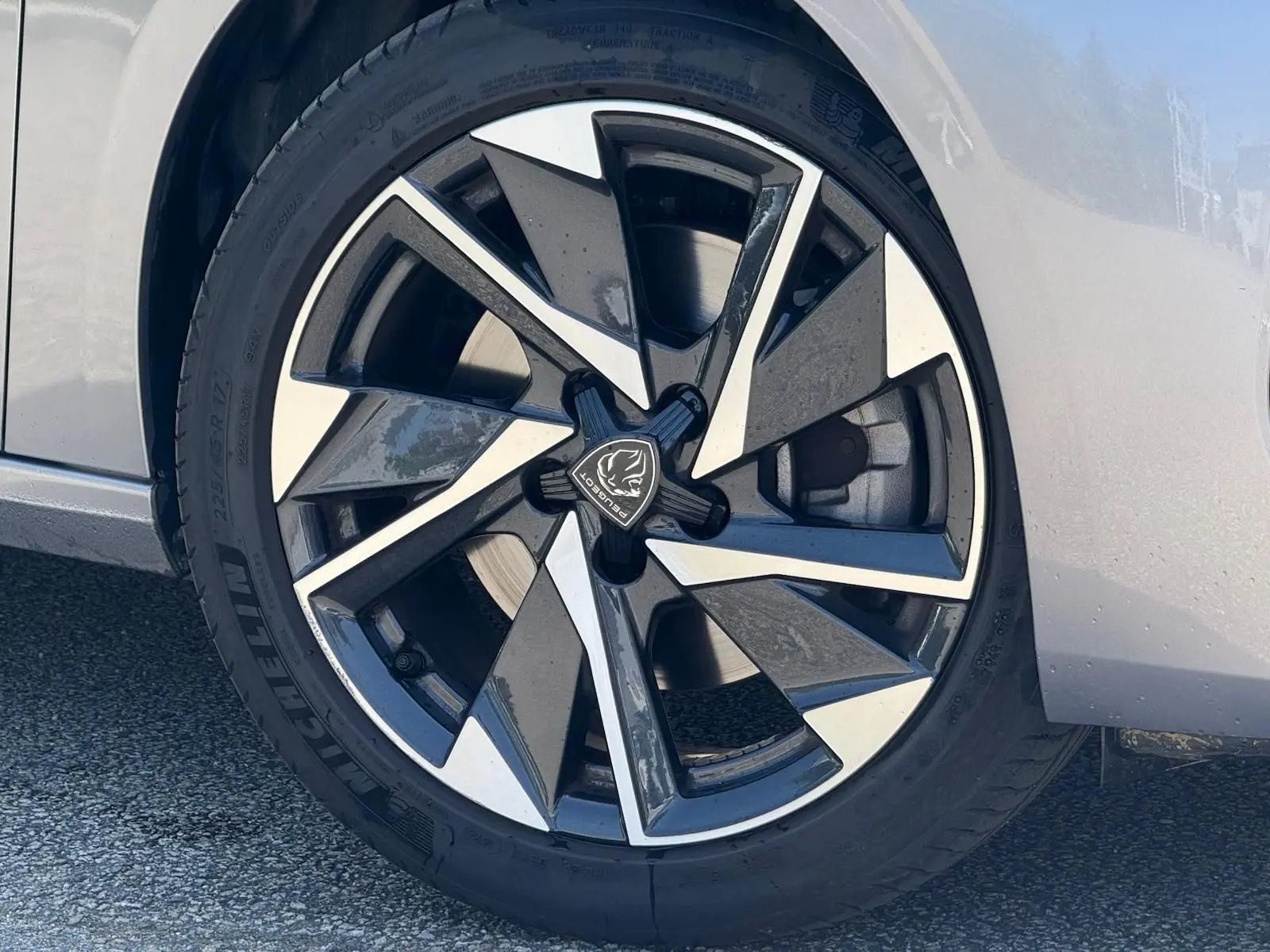 Gros plan sur la jante avant droite de la Peugeot 308 gris Artense avec un design moderne bicolore.