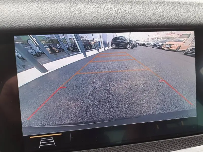 Vue arrière via caméra de recul d'une Opel Insignia Grand Sport blanc glacier en stationnement devant un bâtiment vitré