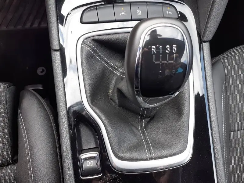 Gros plan sur le levier de vitesse manuel noir avec coutures blanches dans l'habitacle d'une Opel Insignia Grand Sport blanc glacier.