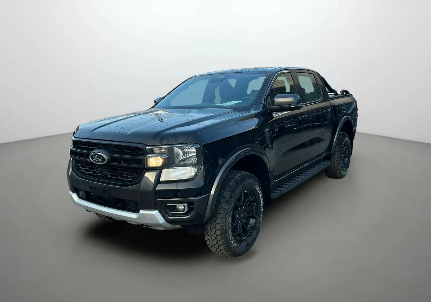 Ford Ranger 2025 noir shadow en 3/4 avant droit avec calandre noire et pneus tout-terrain marqués Tremor Cover.