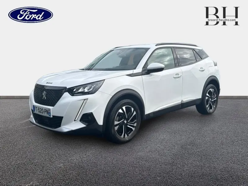 Peugeot 2008 blanc banquise vue 3/4 avant droit avec jantes alu et barres de toit noires.