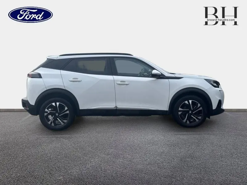 Profil droit d'un Peugeot 2008 blanc banquise de 2020 avec jantes alliage et barres de toit noires.