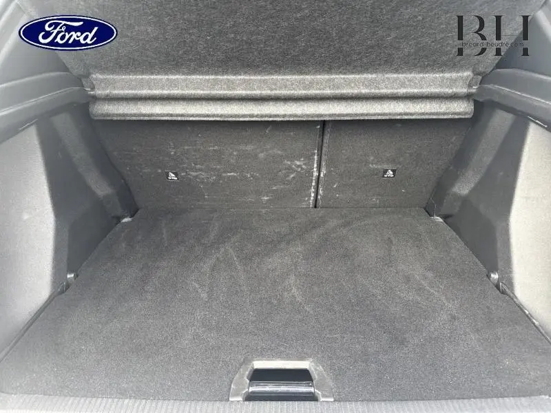 Coffre vide vu de l'intérieur d'un Peugeot 2008 blanc banquise, avec tapis de sol noir et banquette arrière rabattue.