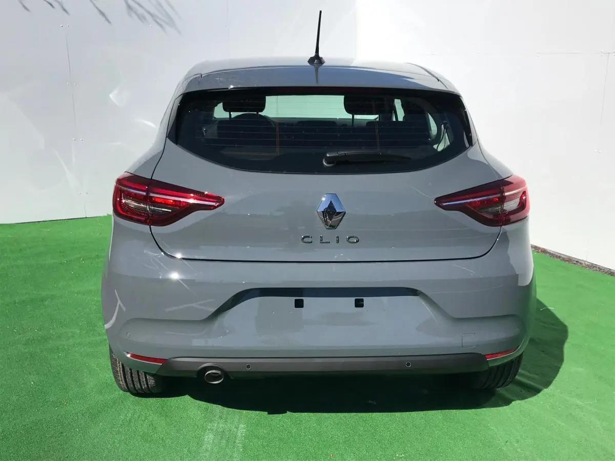Vue arrière d'une Renault Clio 2021 gris Urban avec feux LED et échappement visible sur fond vert.