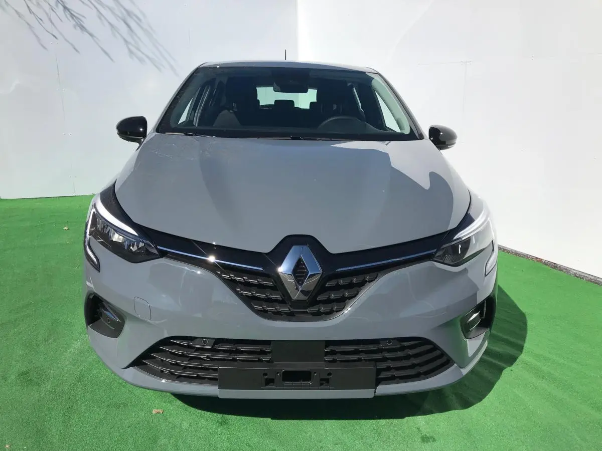 Vue avant d'une Renault Clio gris Urban 2021 avec phares LED et calandre noire brillante sur fond vert.