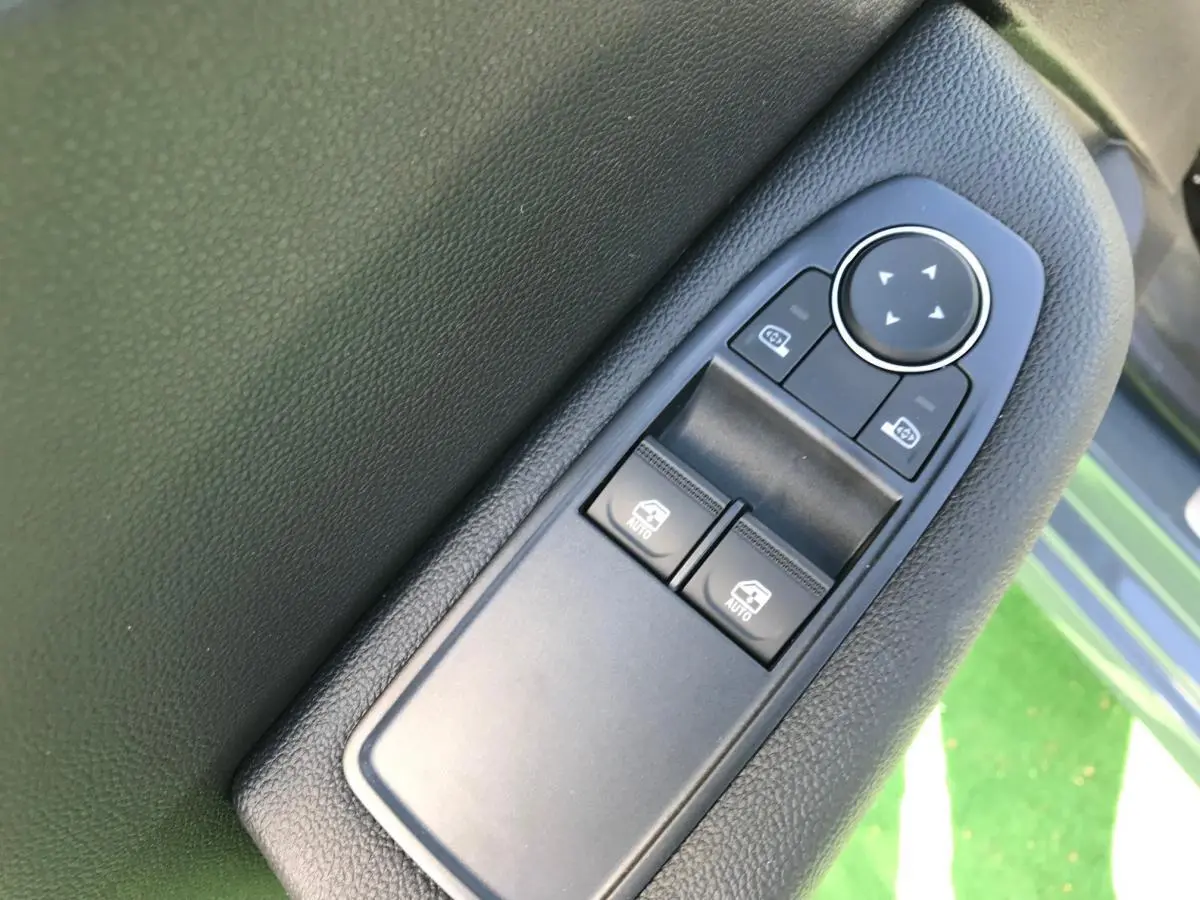 Gros plan sur les commandes des lève-vitres et rétroviseurs côté conducteur d’une Renault Clio 2021 Gris Urban.