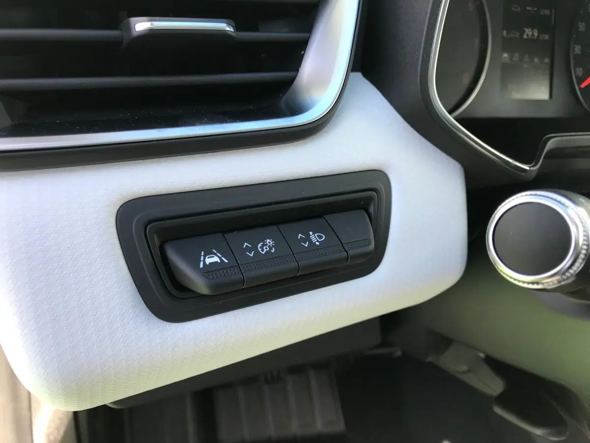 Gros plan sur les commandes d'assistance à la conduite sur tableau de bord blanc de la Renault Clio 2021 Gris Urban.