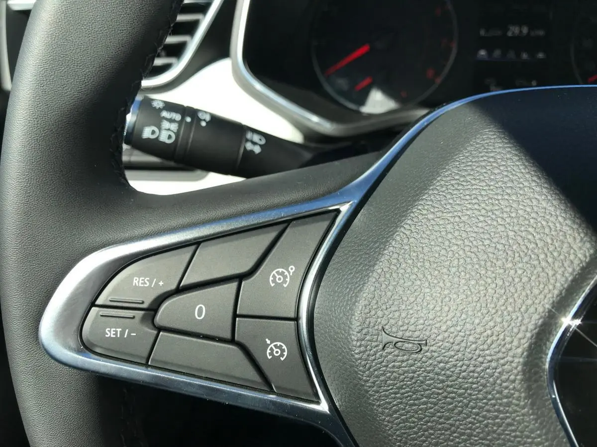 Gros plan sur le volant multifonctions en cuir noir de la Renault Clio Gris Urban, avec commandes de régulateur de vitesse.