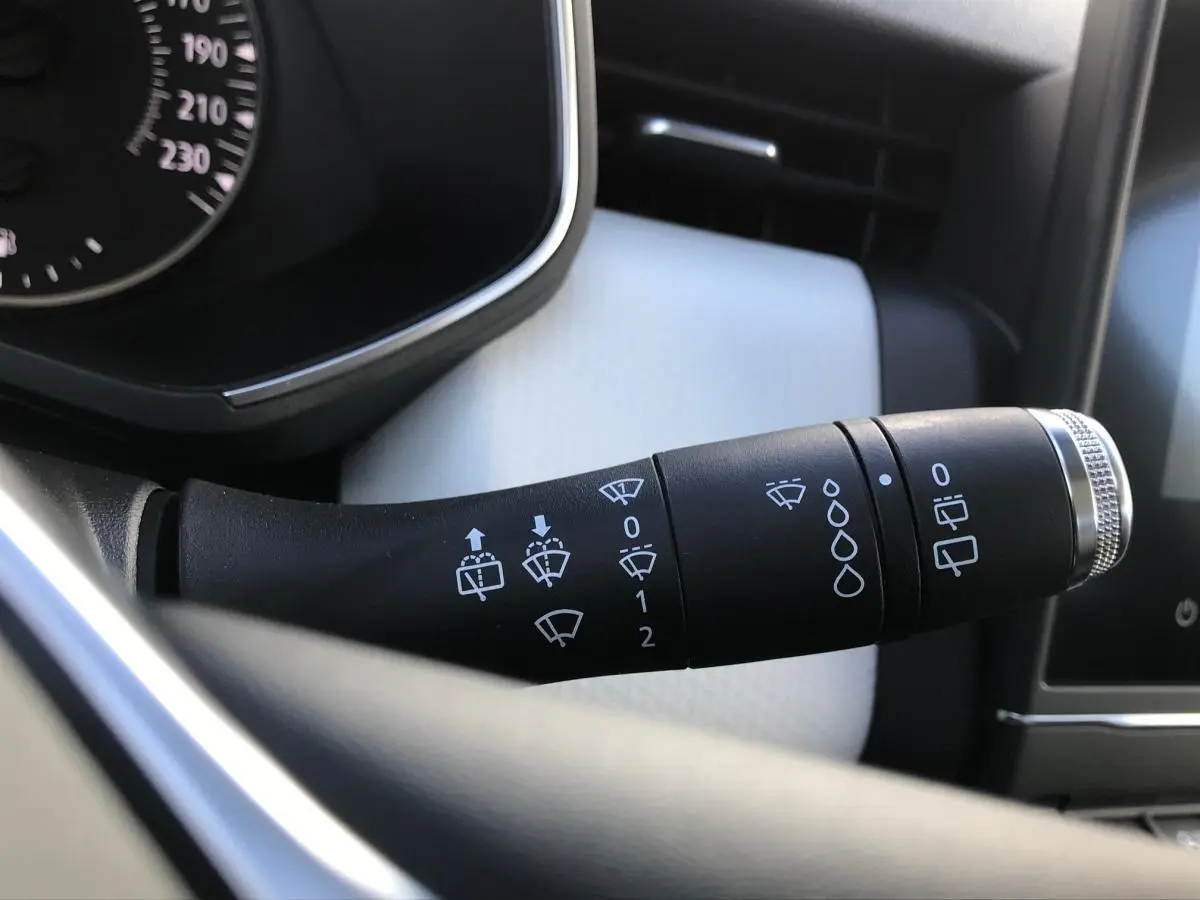 Gros plan sur la commande d'essuie-glaces à gauche du volant dans l'habitacle clair de la Renault Clio Gris Urban 2021.