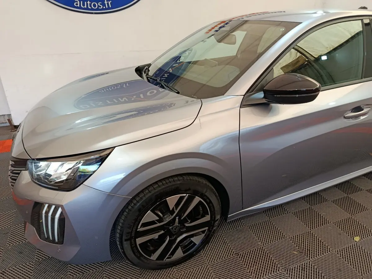 Vue 3/4 avant droit d'une Peugeot 208 gris clair avec phares LED et jantes alliage noires.