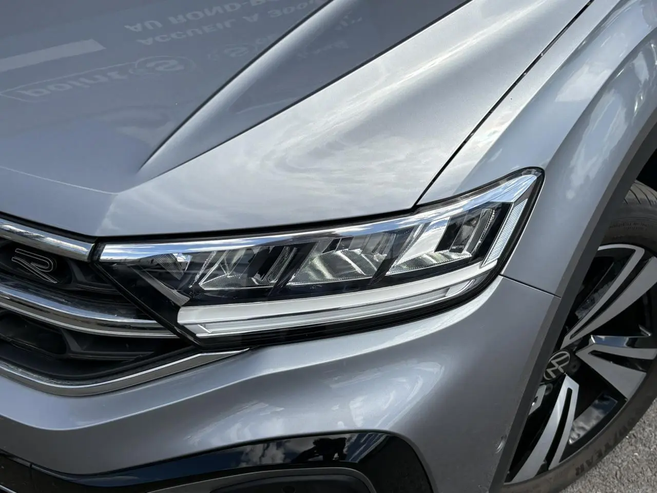 Gros plan sur l'avant droit gris pyrite du Volkswagen T-Roc 2025 avec phares LED et jante alliage R-Line.