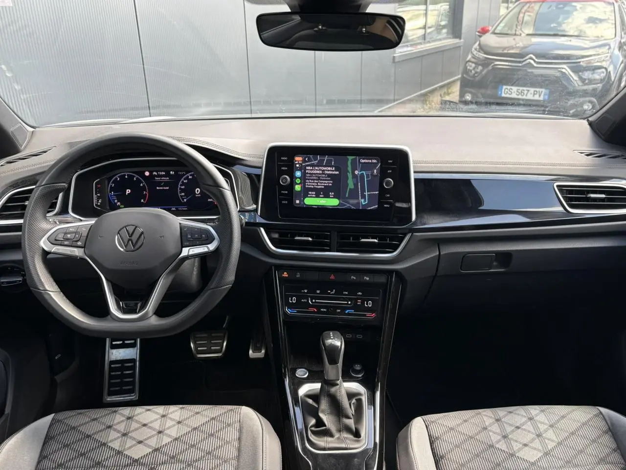 Vue intérieure avant du Volkswagen T-Roc 2025, tableau de bord noir avec écran tactile central et volant multifonction.
