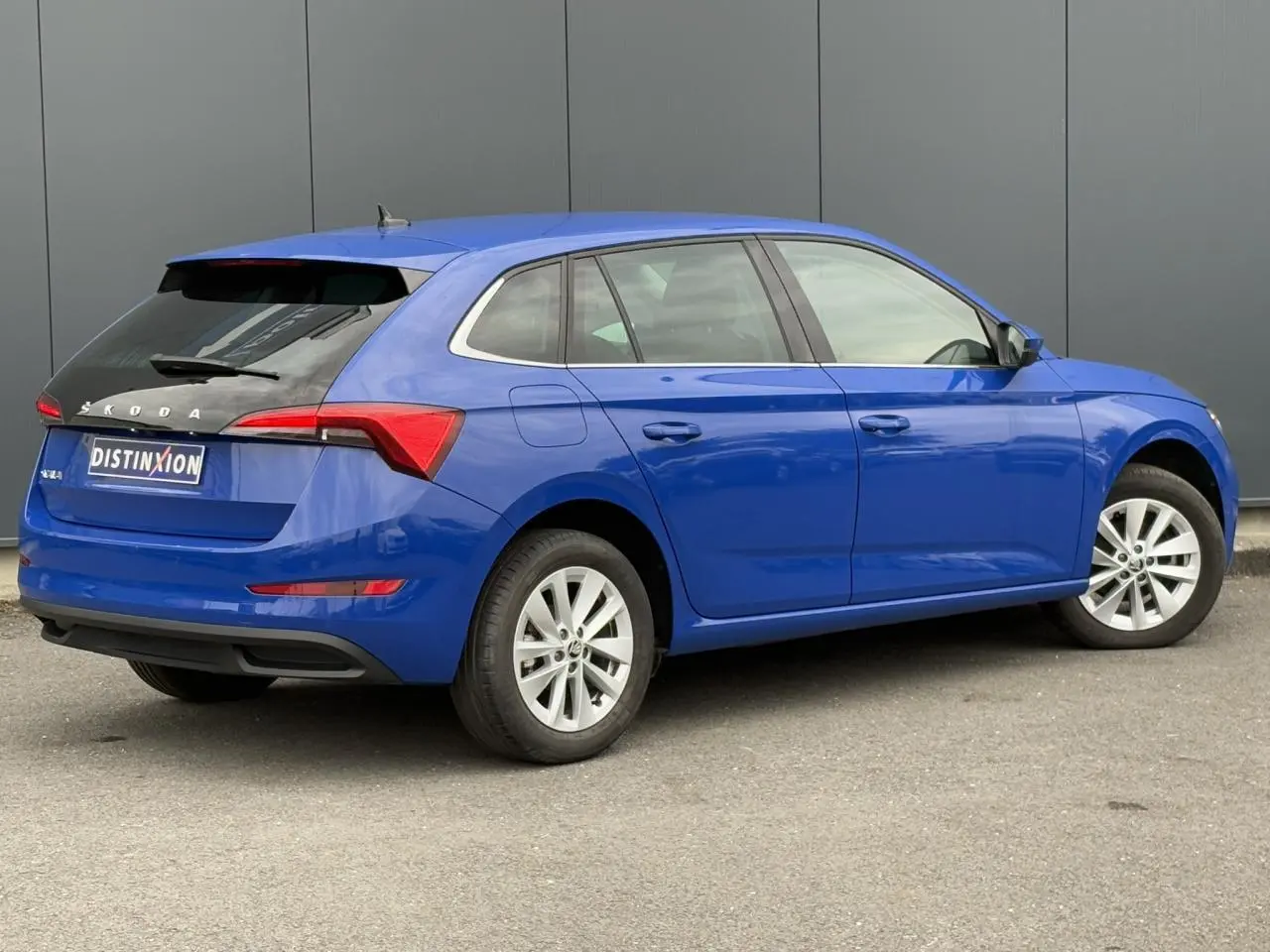 Vue 3/4 arrière droite d'une Skoda Scala 2024 bleu Energy avec jantes alliage argent et toit noir contrasté.