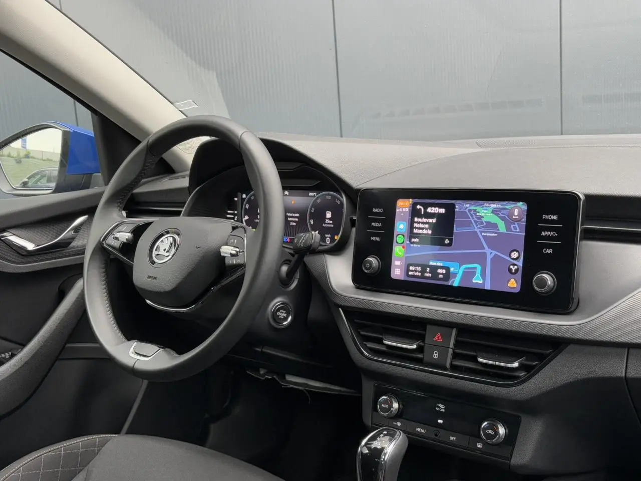 Intérieur de la Skoda Scala bleu Energy, vue côté conducteur sur le volant cuir et l’écran tactile de navigation.