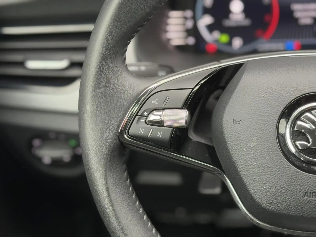Gros plan sur les commandes gauche du volant cuir multifonctions du Skoda Scala TSI 110 DSG Ambition 2024.