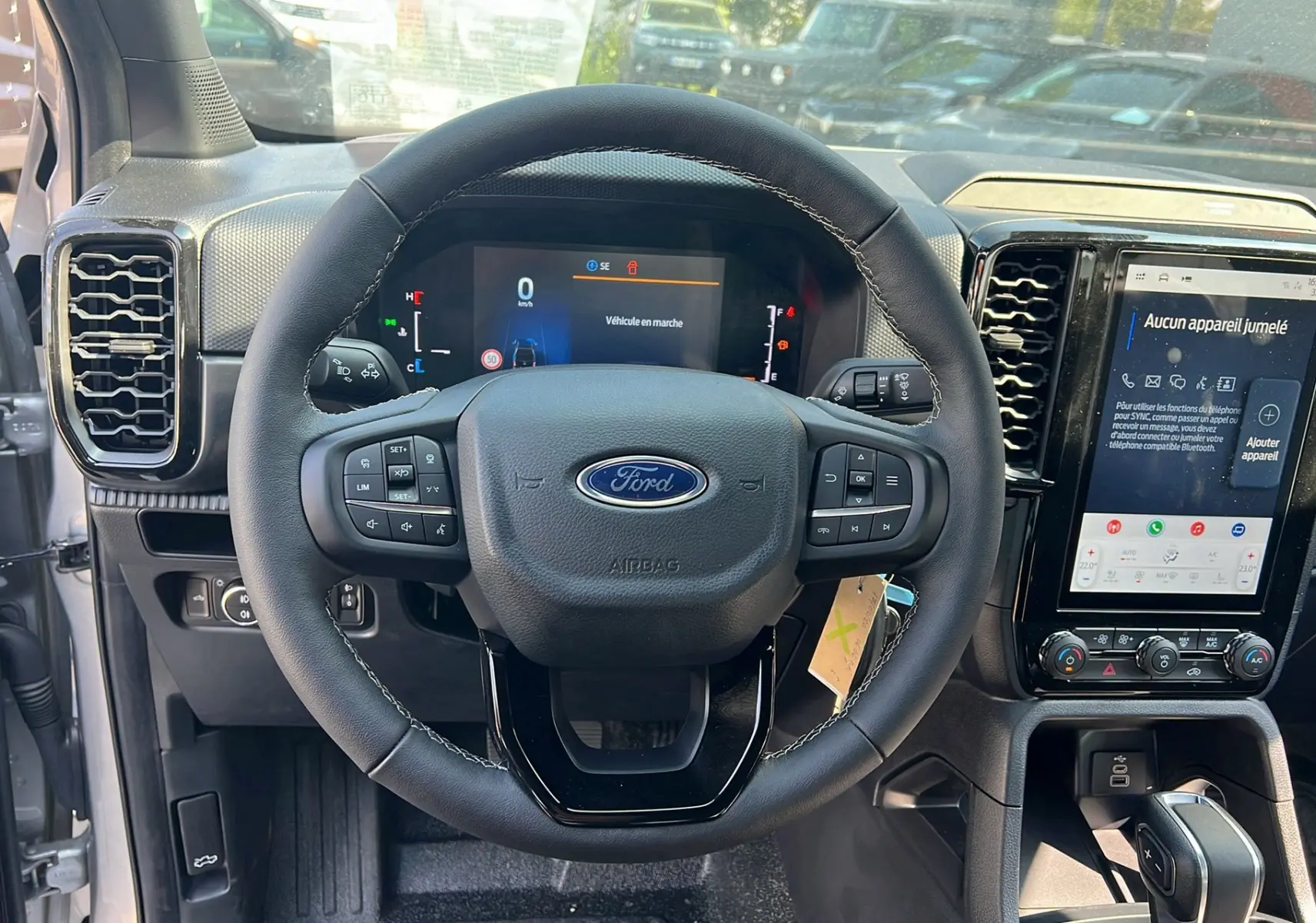 Vue intérieure centrée sur le volant du Ford Ranger 2025 gris iconic avec tableau de bord digital et écran tactile vertical.