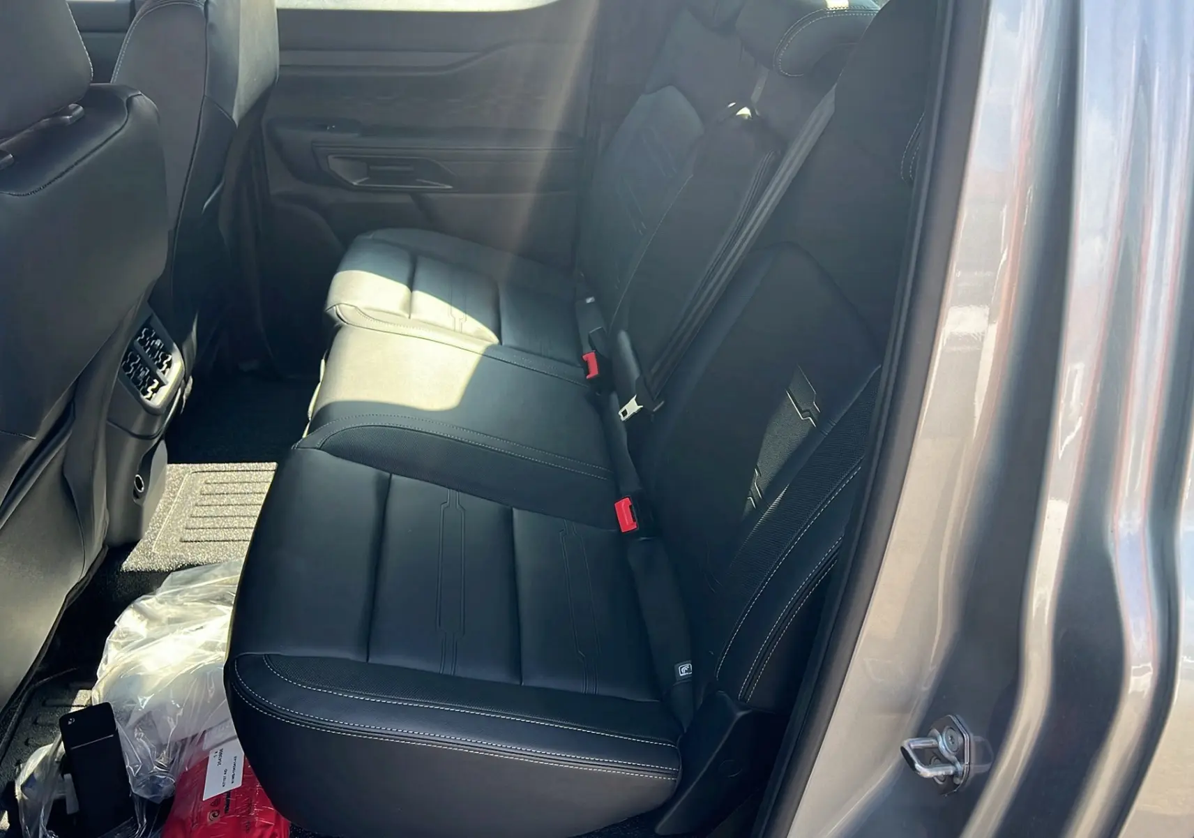 Vue intérieure côté droit des sièges arrière en cuir noir du Ford Ranger 2025 gris iconic, avec ceinture de sécurité rouge visible.
