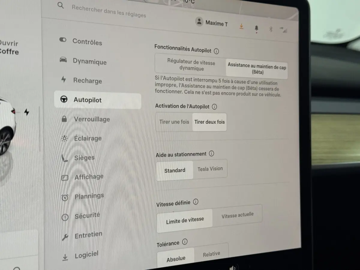 Écran tactile central affichant les réglages Autopilot dans l'habitacle d'une Tesla Model Y blanche de 2022.
