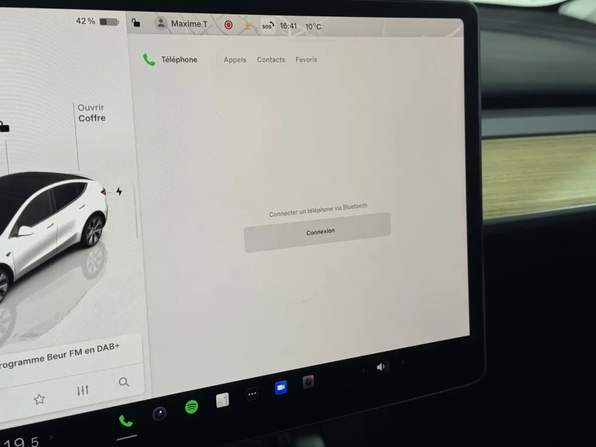 Écran tactile central affichant la connectivité Bluetooth dans l'habitacle d'une Tesla Model Y blanc 2022.