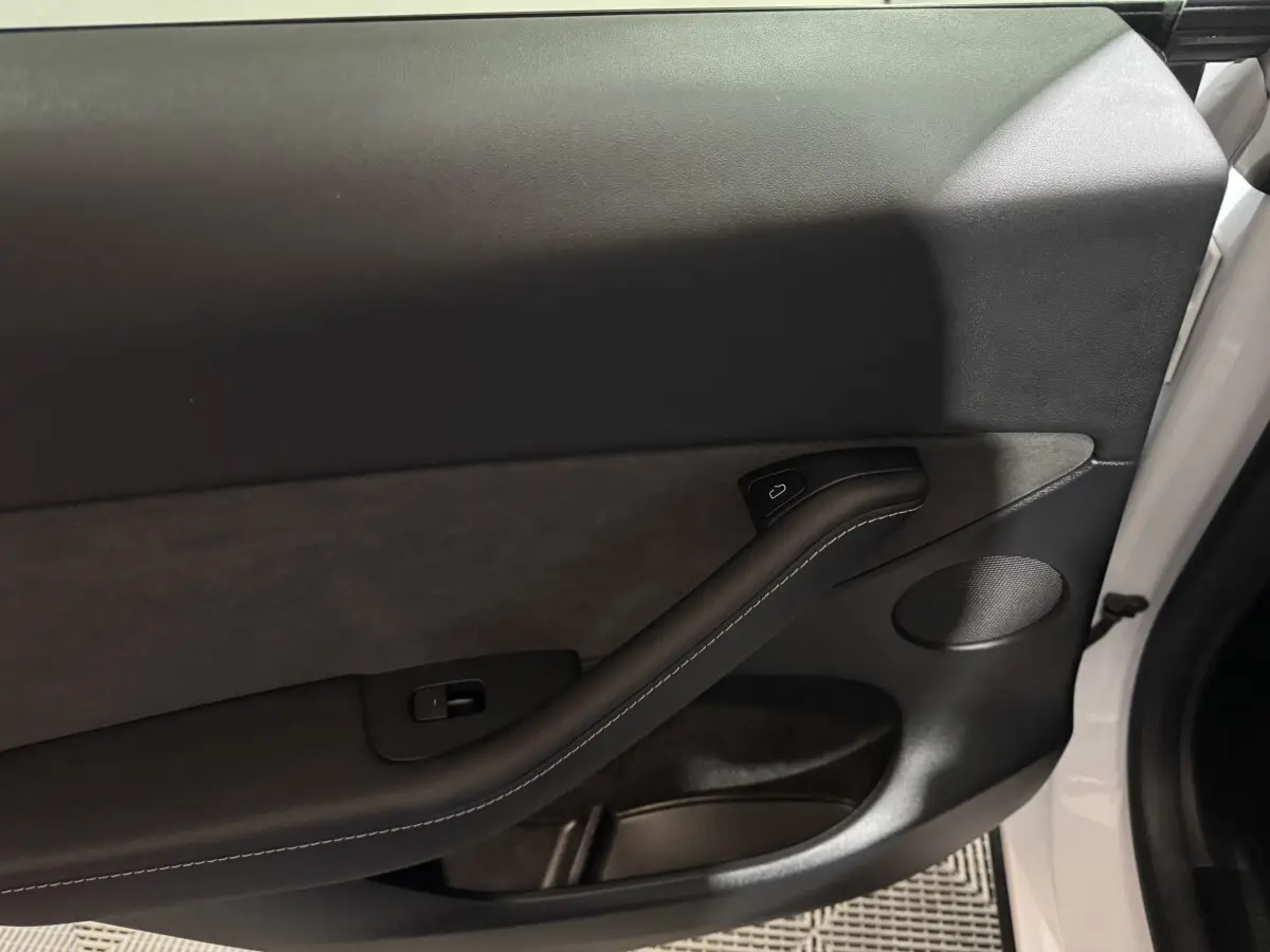 Gros plan sur la porte intérieure côté gauche blanche d'une Tesla Model Y 2022 avec garniture noire et poignée intégrée.