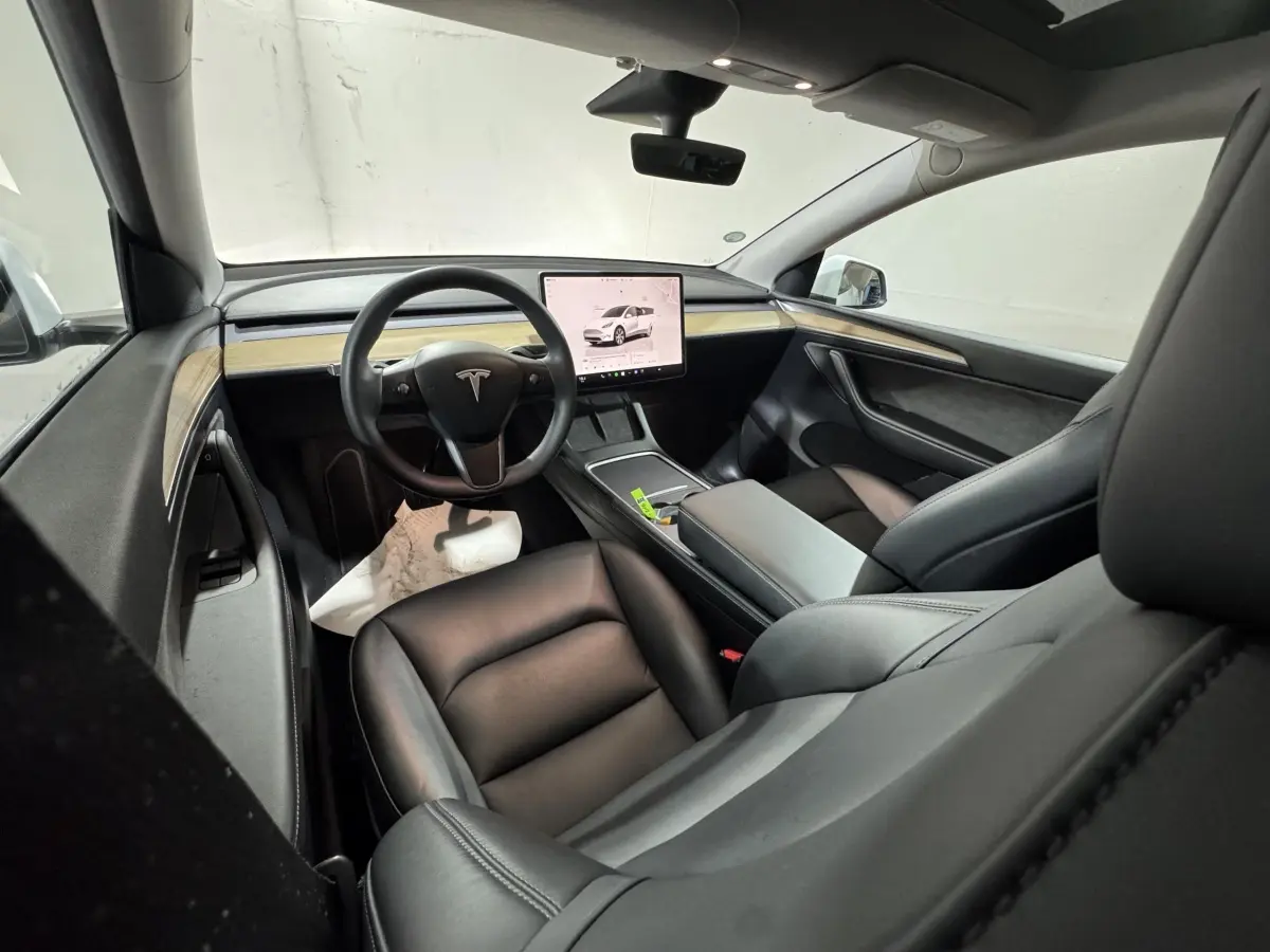 Intérieur noir de Tesla Model Y 2022, vue depuis l'arrière droit, avec tableau de bord minimaliste et écran tactile central.