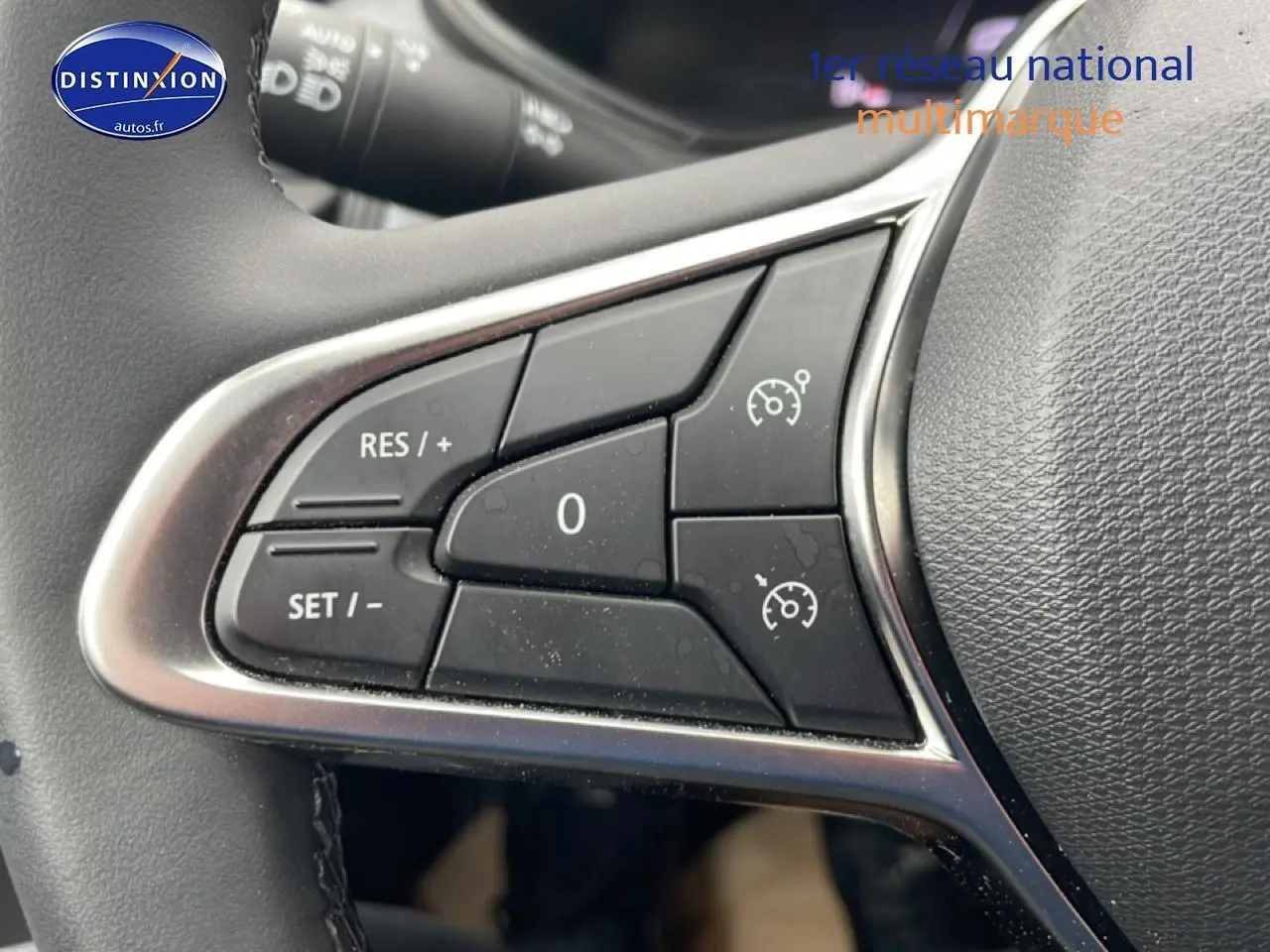 Gros plan sur les commandes du régulateur de vitesse au volant d’une Renault Clio V blanche, version 2025.
