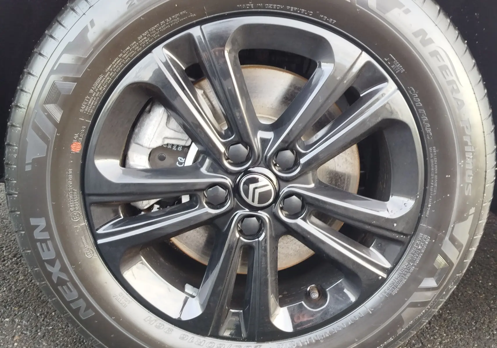 Gros plan sur la jante noire brillante avec logo Citroën au centre, montée sur un pneu Nexen du Berlingo blanc.