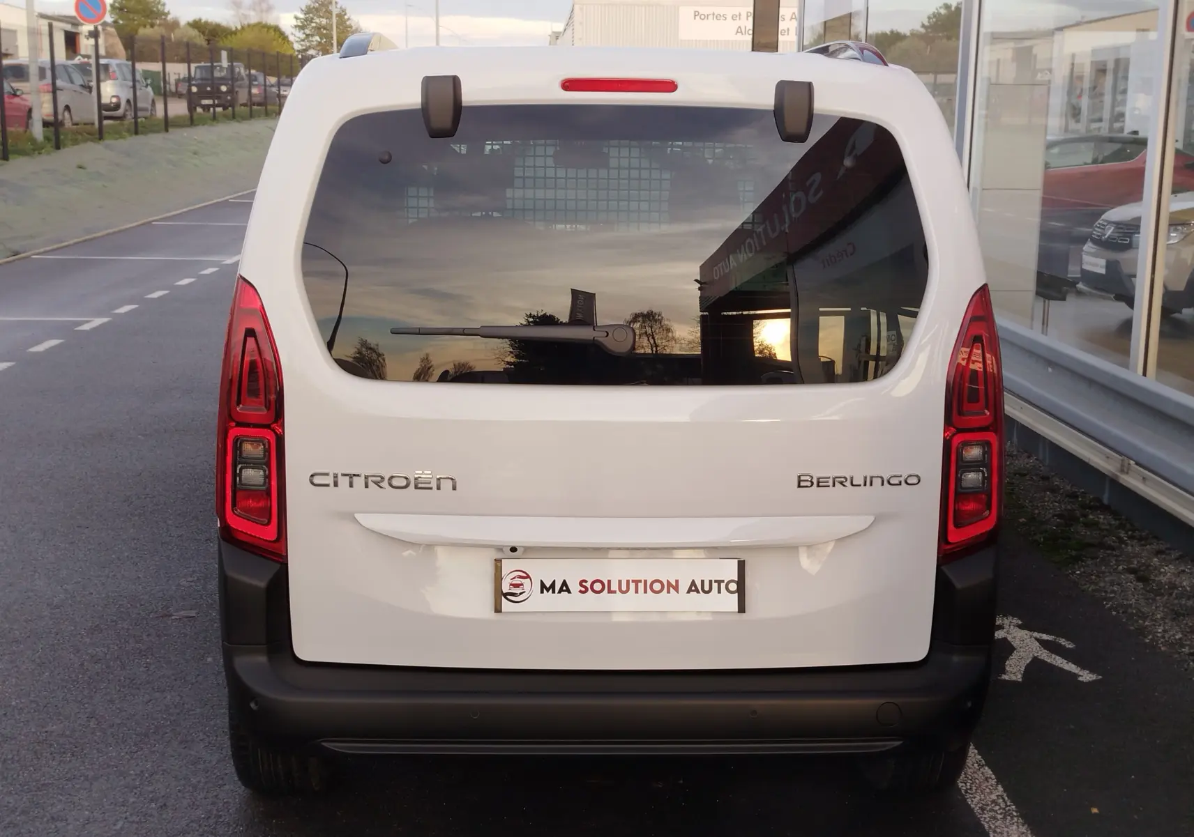 Vue arrière d'un Citroën Berlingo blanc Kaolin avec vitres teintées et feux arrière verticaux allumés.