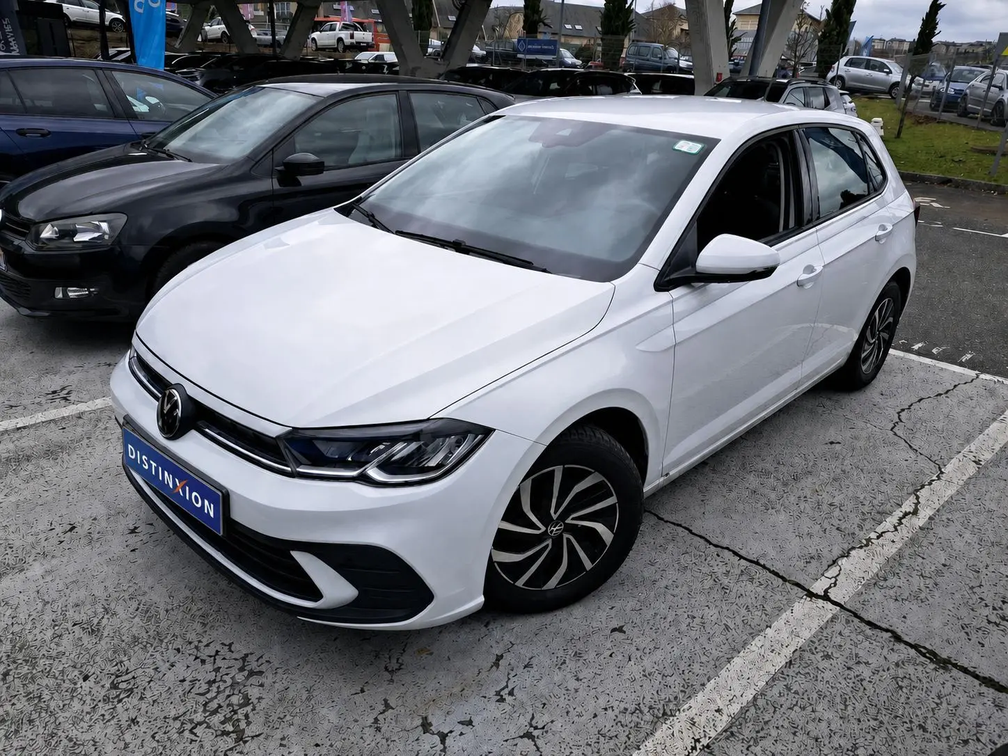 Volkswagen Polo 1.0 TSI blanche vue en 3/4 avant droit sur parking avec jantes noires et blanches.