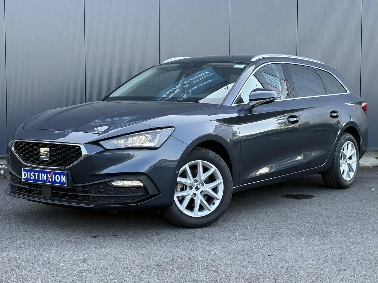 SEAT LEON ST gris magnétique en 3/4 avant droit, jantes alliage 16 pouces et vitres arrière surteintées visibles.
