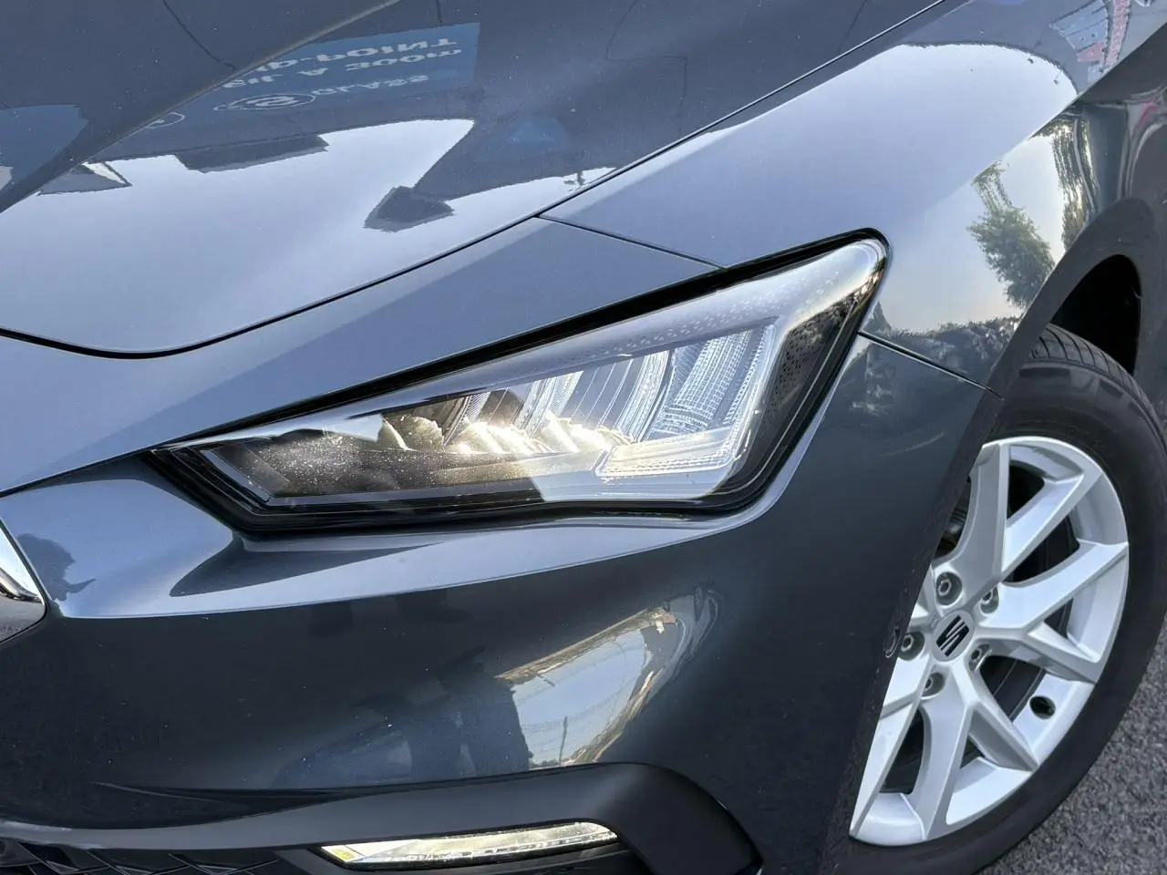 Gros plan sur l'avant droit gris magnétique du SEAT LEON ST 2025, mettant en valeur le phare LED et la jante alliage 16 pouces.