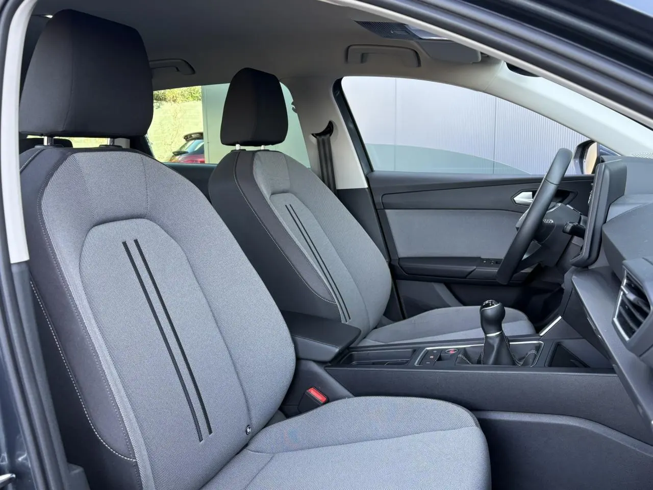 Vue intérieure côté droit du SEAT LEON ST 1.5 TSI 115 Style 2025, sièges textile gris clair avec console centrale noire.