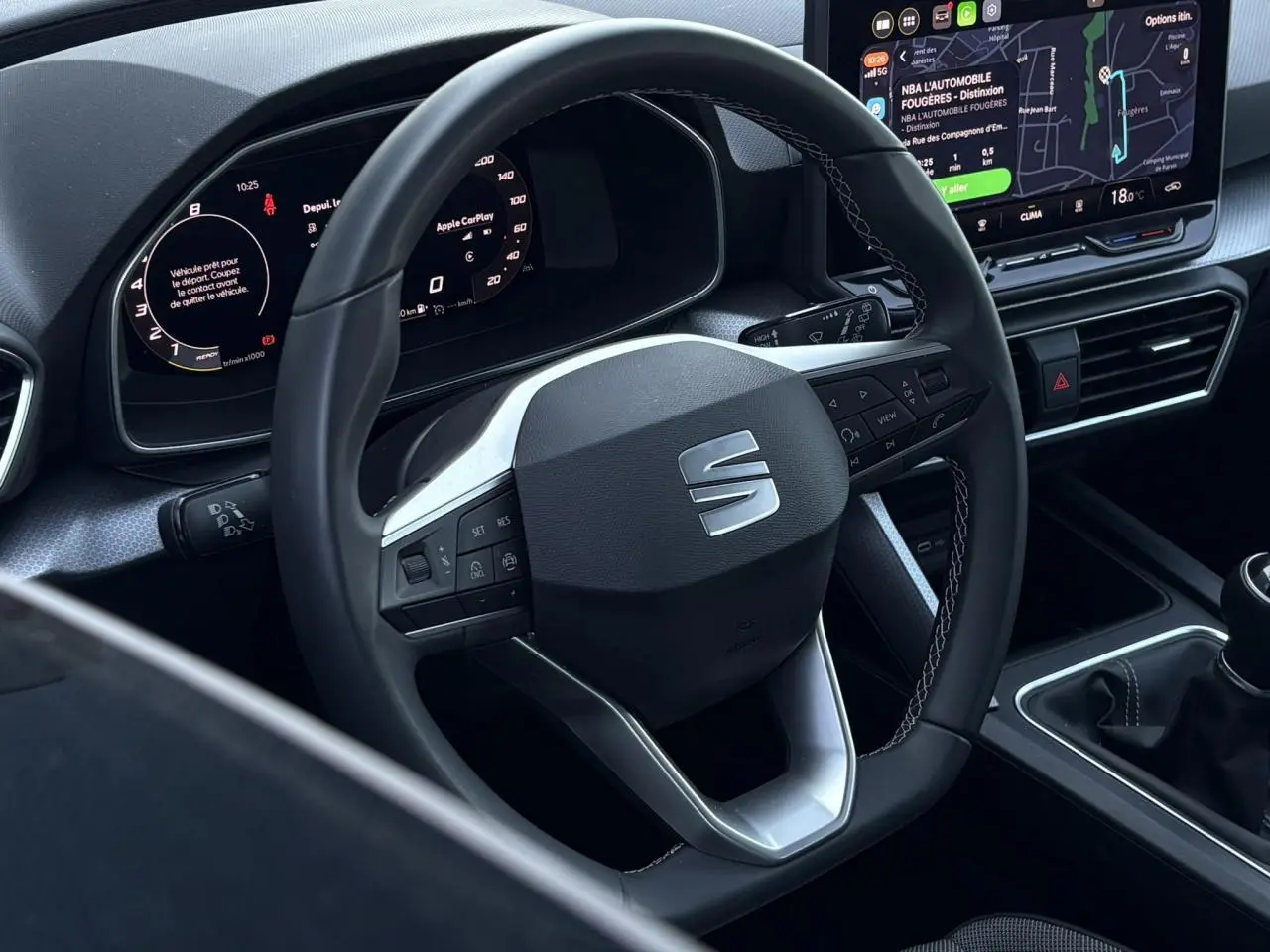 Vue intérieure centrée sur le volant cuir multifonction SEAT, tableau de bord numérique et écran tactile avec navigation.