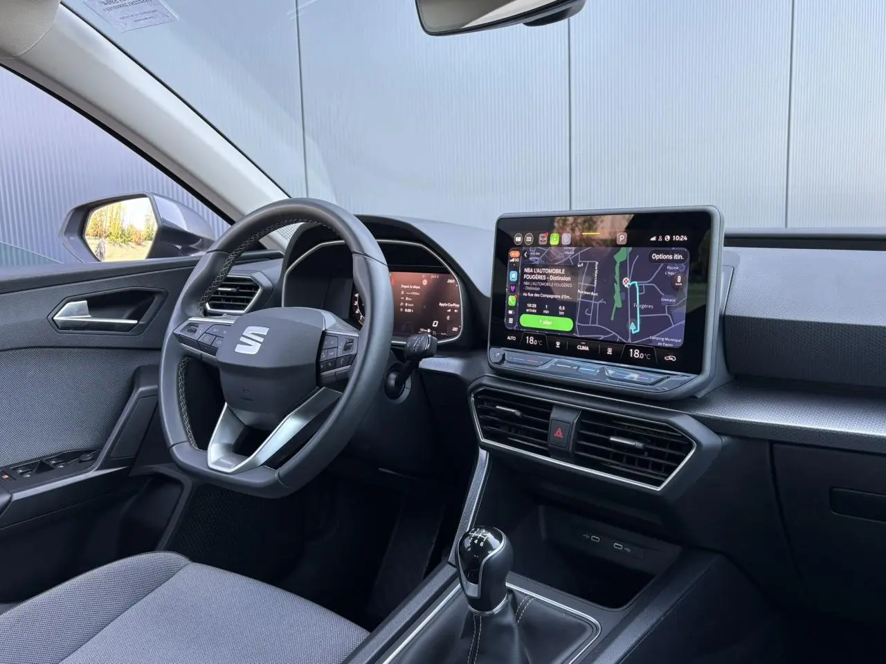 Vue intérieure côté conducteur du SEAT Leon ST 2025, avec volant cuir multifonction et écran tactile central lumineux.
