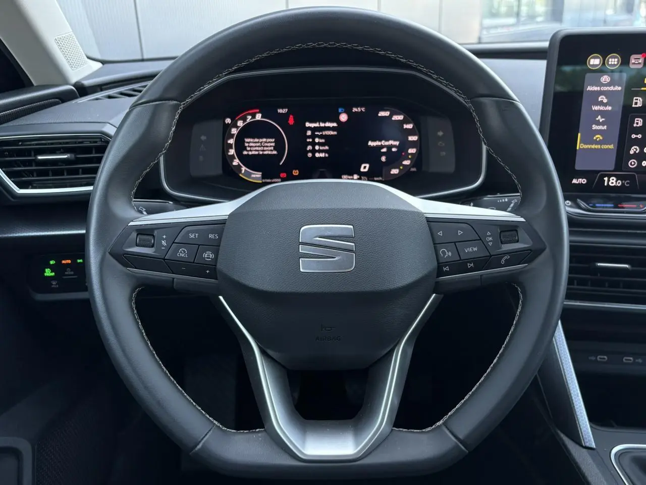 Vue centrée sur le volant cuir multifonction de la SEAT LEON ST 2025 avec tableau de bord numérique et écran tactile.
