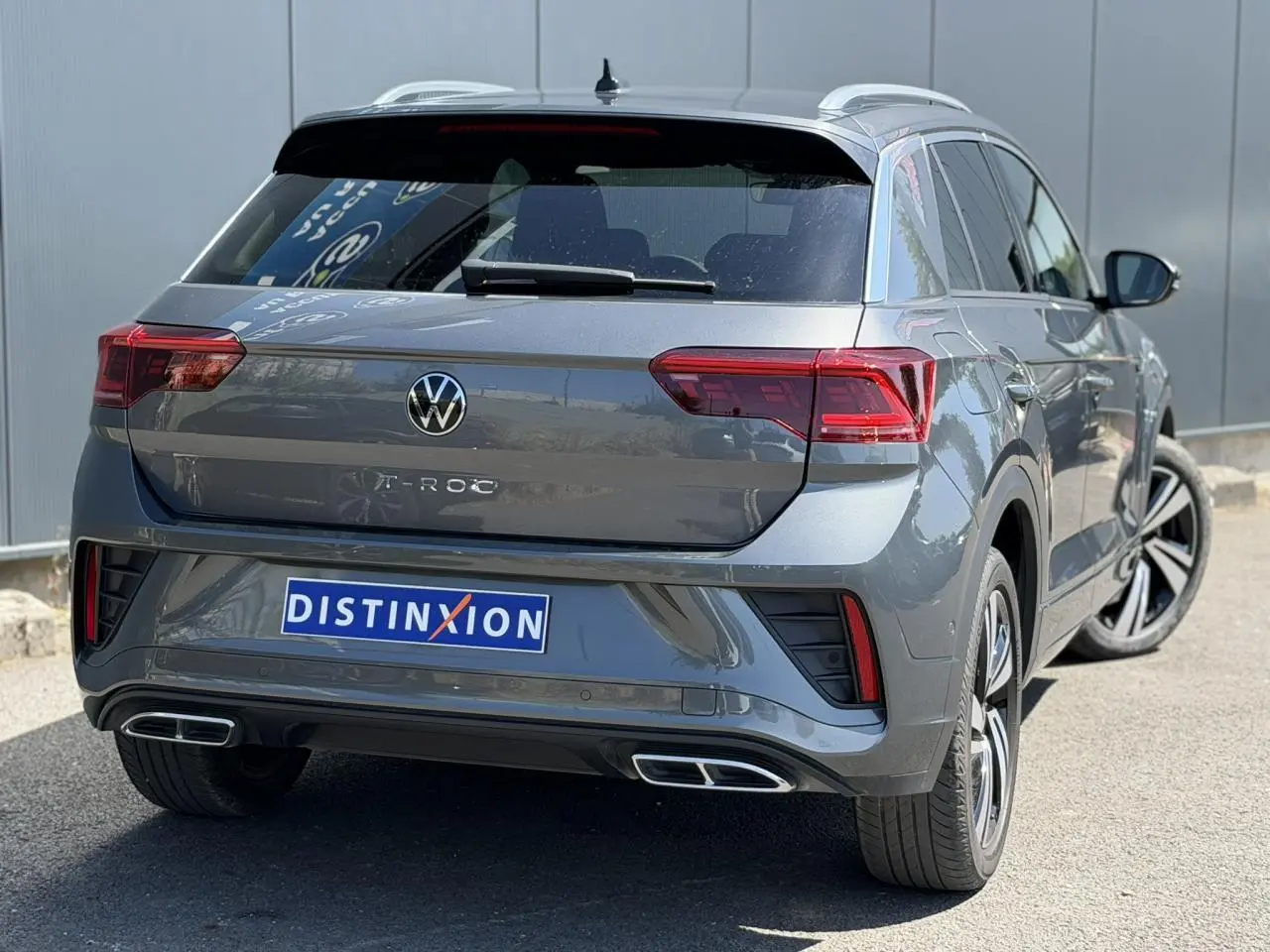 Vue 3/4 arrière droite du Volkswagen T-Roc gris Indium avec feux Matrix LED et double sorties d’échappement rectangulaires.