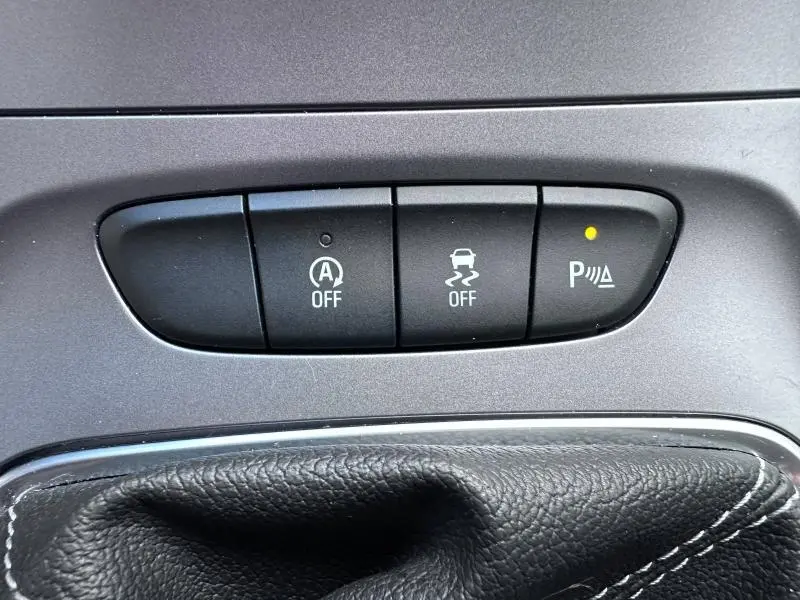 Gros plan sur les boutons de contrôle du système d'assistance au stationnement et de stabilité dans l'Opel Astra Sports Tourer gris cosmique.