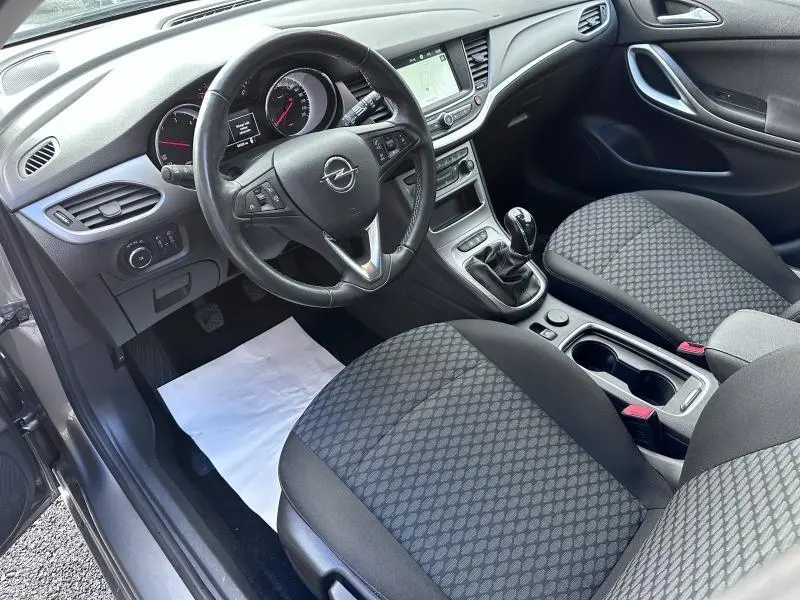 Vue intérieure côté conducteur de l'Opel Astra Sports Tourer 2021 avec volant cuir multifonction et sièges tissu gris.