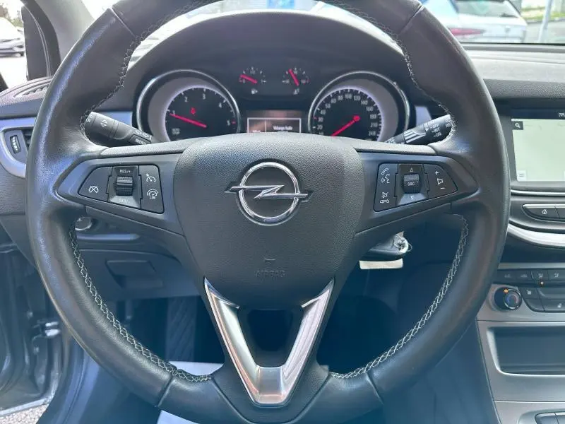 Vue rapprochée du volant cuir multifonction de l'Opel Astra Sports Tourer 2021, avec tableau de bord et écran tactile visibles.