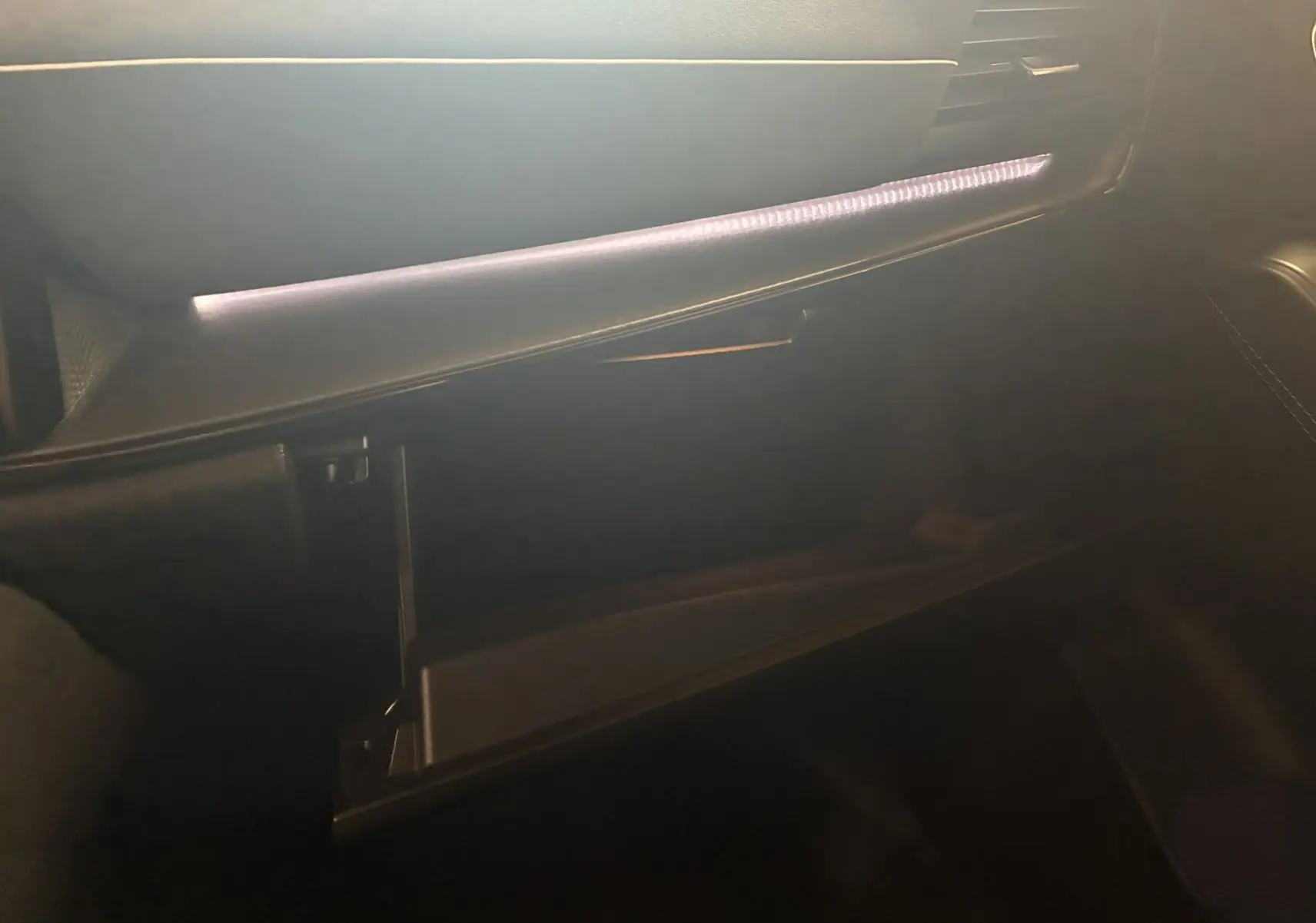 Gros plan sur la boîte à gants ouverte du Nissan Qashqai 1.5 VCT E-POWER 2025 avec éclairage intérieur subtil.