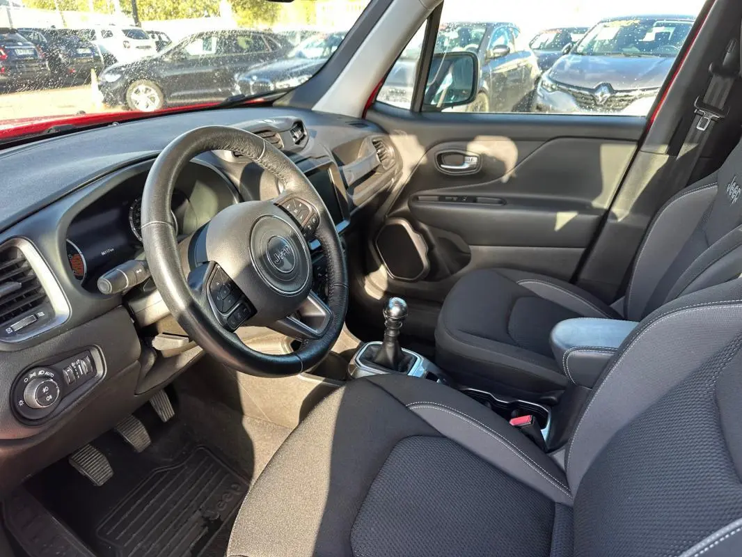 Intérieur du Jeep Renegade 2022, vue côté conducteur, volant cuir, sièges tissu gris et accoudoir central.