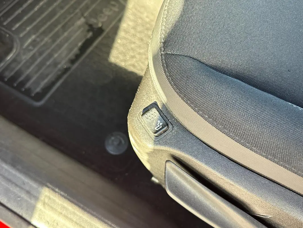 Gros plan sur le bouton de réglage lombaire du siège conducteur en tissu noir dans une Jeep Renegade 2022.