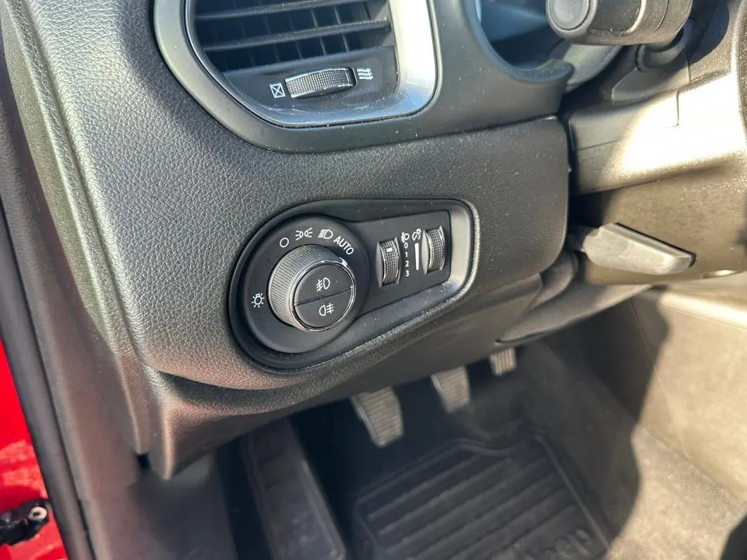 Gros plan sur le tableau de bord côté gauche du Jeep Renegade rouge, montrant la commande des phares et les pédales.